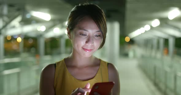 Woman look at smart phone in city at night