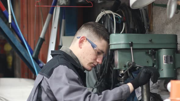 Mechanic wearing glasses working at drilling machine