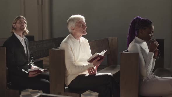 Three Multiethnic Parishioners Praying in Catholic Church