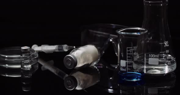 Laboratory Equipment: Syringe and Medicine, Test Tubes and Flasks Rotating on Black Background.