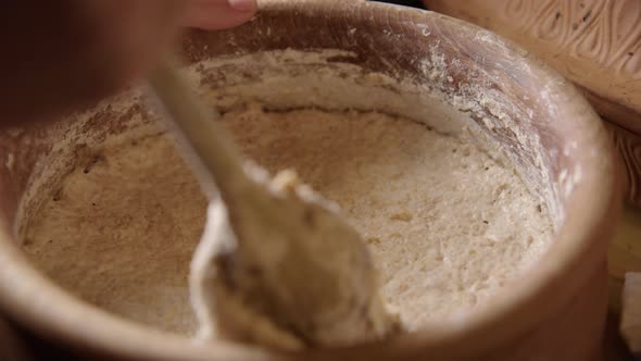 BAKING - Mixing sourdough bread dough with a wooden spoon, slow motion close up