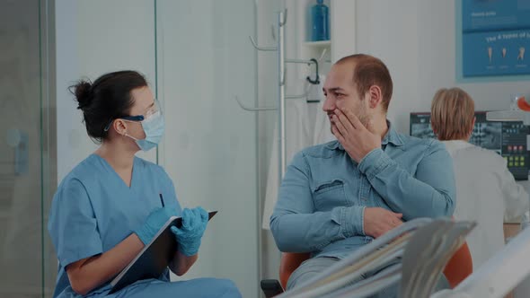 Patient Explaining Toothache to Dentistry Nurse at Stomatology Visit