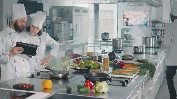 Man and Woman Analyzing Culinary Recipe on Digital Tablet