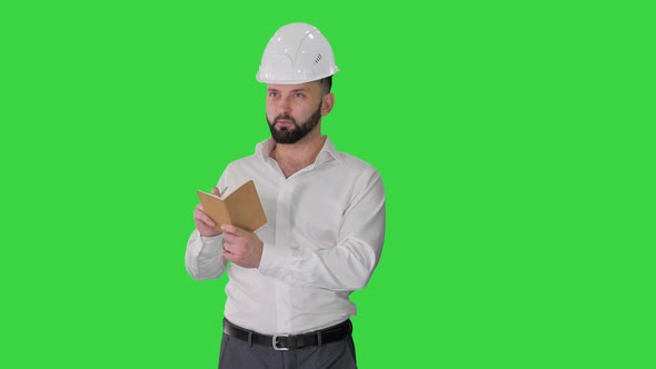 Confident Mature Man in Formalwear and Hardhat Writing Down Notes on a Green Screen Chroma Key