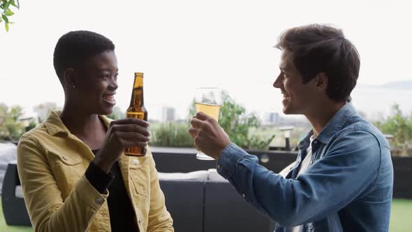 Two friends drinking a beer and discussing on a rooftop