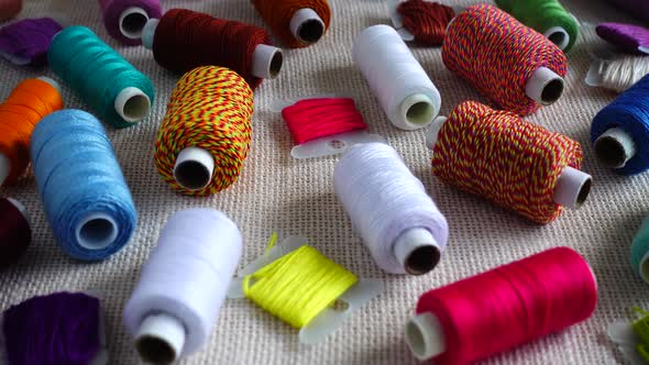 A top view of colorful mouline threads and multicolored spools isolated on a burlap background.