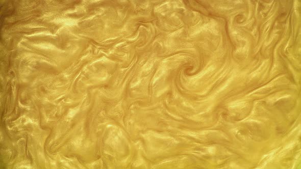 The Gold Powder Is Mixed in the Water. Top View of Streams of Golden Luster Mixing in the Liquid