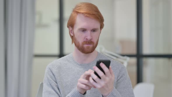 Portrait of Young Redhead Man Using Smartphone