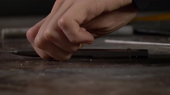 Hand takes a pen for metal from the table