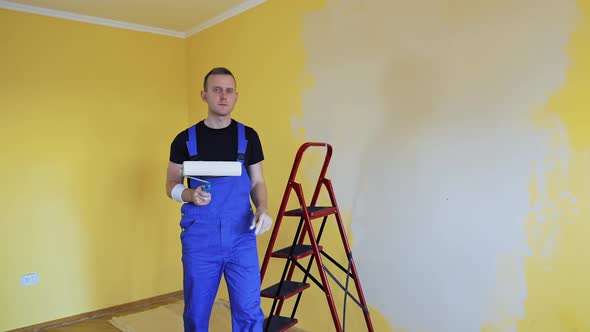 Workman in the uniforms painting the walls with paint roller