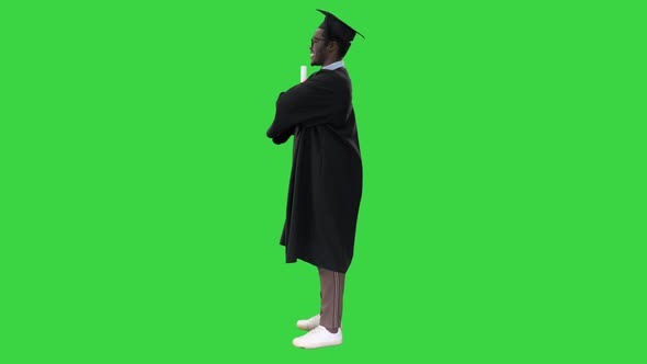 African American Male Student in Graduation Robe Folding Arms with Diploma Looking with a Big Smile