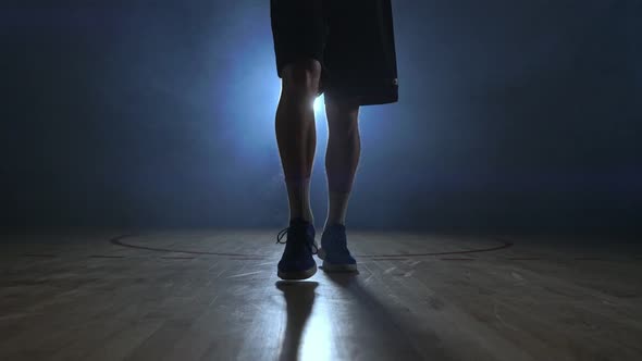 Male Basketball Player Moving in the Smoke at the Camera Knocking the Ball About the Parquet Ground