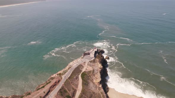 Aerial High view Seascape Landmark Lighthouse on cliffside, Nazaré - Portugal