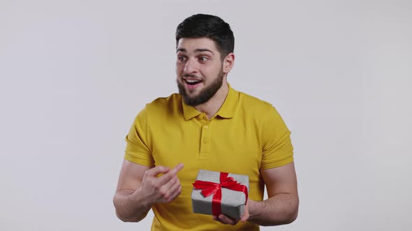 Young Man Holding Gift Box with Bow He Wonders What is Inside