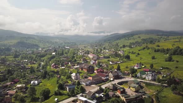 Aerial view of a small village between green summer hills in ukrainian Carpathian mountains