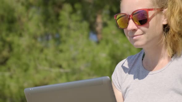 woman works on laptop on beach.