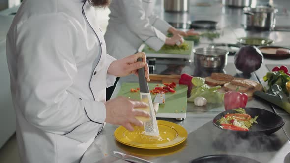 Male Chef Grating Parmesan Cheese on Kitchen Grater