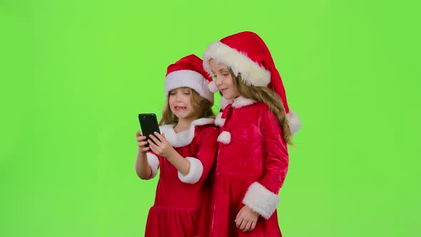 Baby Girls in New Year Costumes Do Selfie on the Phone, Green Screen