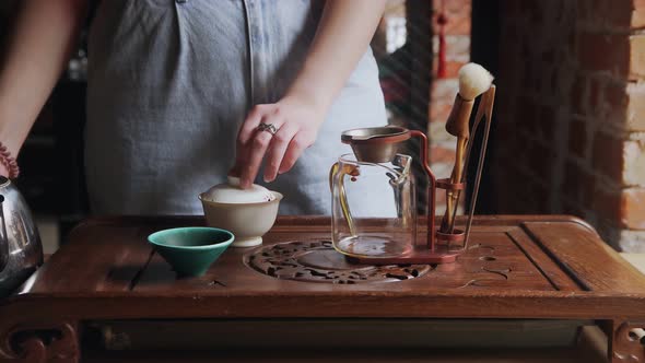 Close Up of Woman Pouring Green Tea From Gaiwan to Glass Teapot