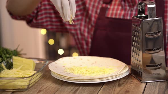 Young Caucasian Chef in Uniform Cooking Enchilada with Grated Cheese Filling in Tortilla with Food