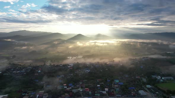 Landscape view of the city of rural village in valley on foggy day while the sun is raising by drone