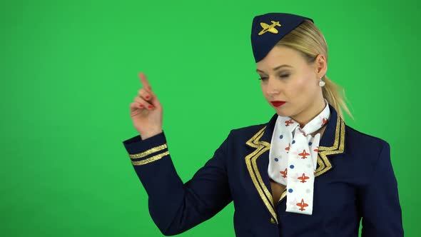A Young Stewardess Taps Her Watch at the Camera and Points a Finger To the Sky - Green Screen Studio