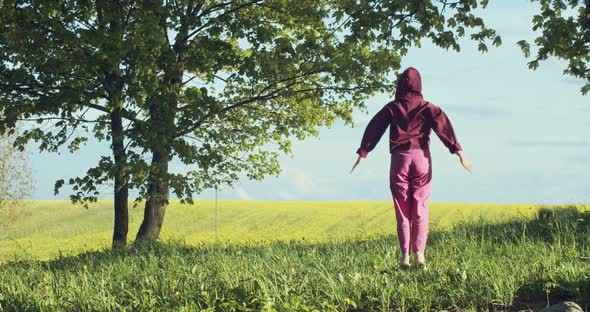 Back View of Girl in Pink Sportswear Training Outdoors in Countryside on Yellow Field Background