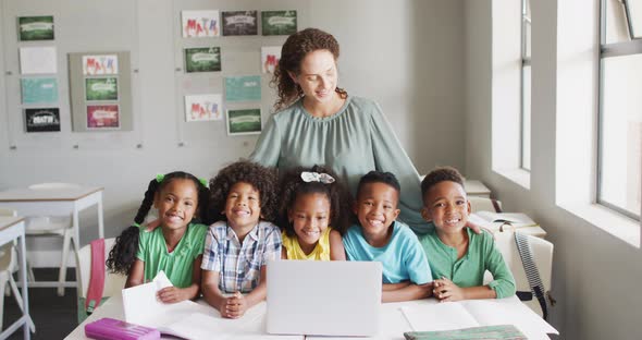 Video of happy caucasian female teacher and class of diverse pupils smiling at camera