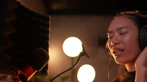 young woman singer or musician working for recording the music in studio, wearing earphones