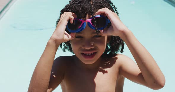 Portrait of happy biracial boy looking at camera in swimming pool