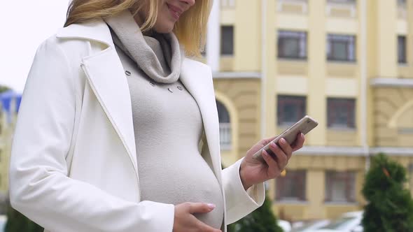 Pretty Pregnant Female Using Mobile App to Navigate in Big City, Taxi Service