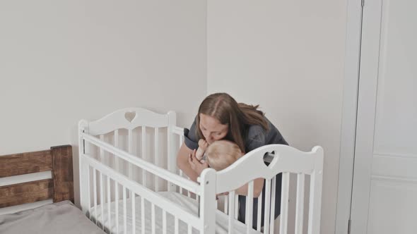 Woman Putting Toddler into Crib