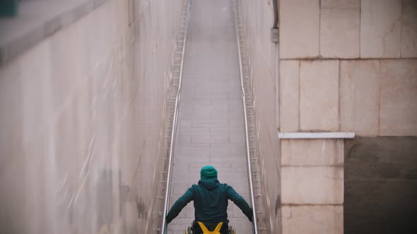 Disabled Man in Wheelchair Getting Up on the Long Special Ramp with an Effort