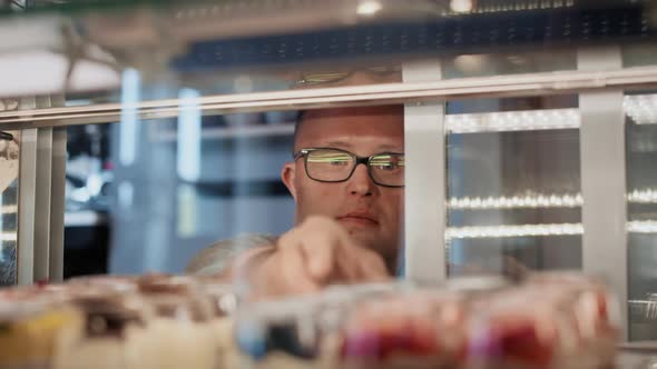 Caucasian man with down syndrome taking a dessert from the fridge to serve in a cafe. Shot with RED