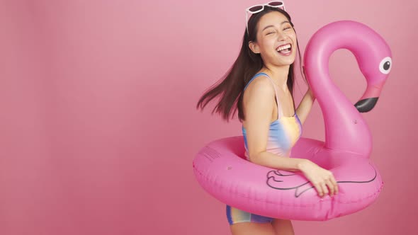 Beautiful Sexy asian woman in bikini and smiling standing  on pink background