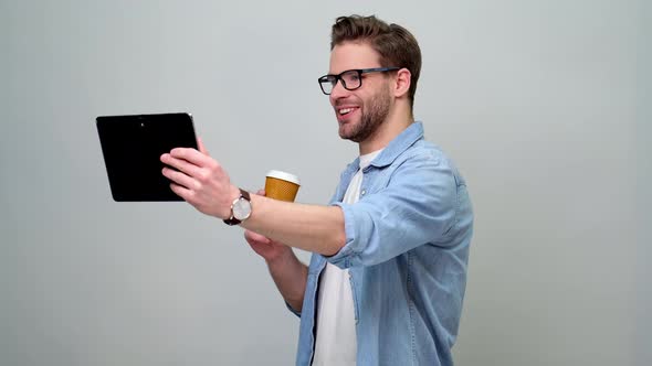 Bearded young caucasian man wearing jeans shirt using tablet pc pad