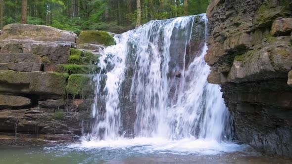 Waterfall on Mountain River with White Foamy Water Falling Down From Rocky Formation in Summer