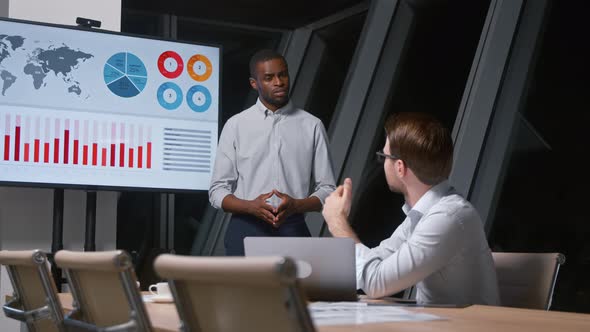 Corporate manager asking question to colleague giving presentation