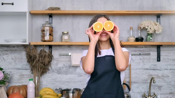 Adorable Playful Vegan Housewife Posing with Slice Fresh Orange on Eyes Having Fun Zoom in Shot