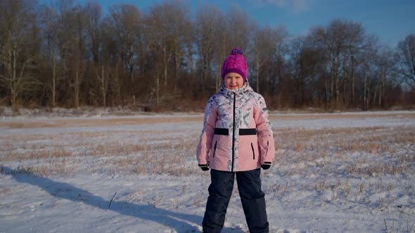Cute child portrait standing looking at camera at winter outdoors. Female person school age