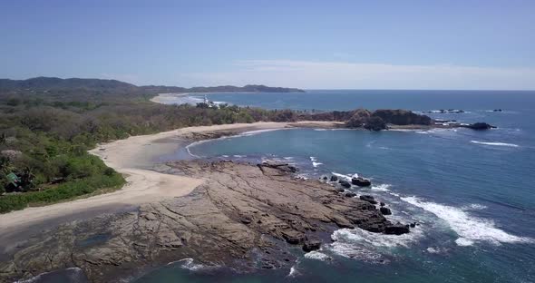 Aerial drone view of the beach, rocks and tide pools in Playa Palada, Guiones, Nosara, Costa Rica.