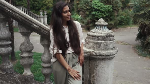 Cheerful Pretty Girl Is Standing in Garden in Old Park in Background of Stair