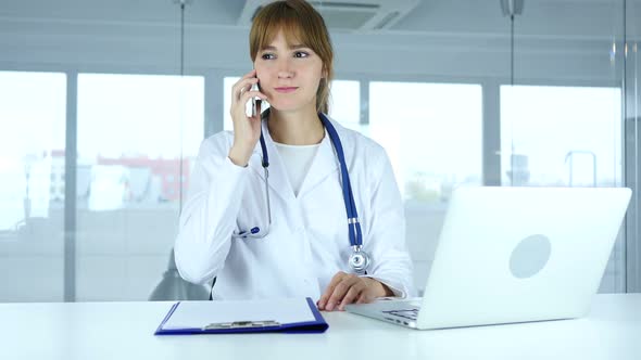 Young Female Doctor Talking on Phone in Hospital