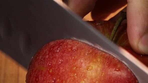 Very sharp knife cuts a slice out of a red apple, macro shot. Detailed close up in 4K.