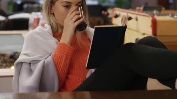 Caucasian woman drinking coffee and reading a book