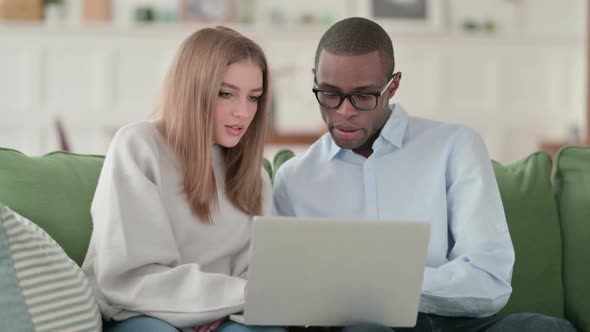 Mixed Race Couple Excited While Working on Laptop Home