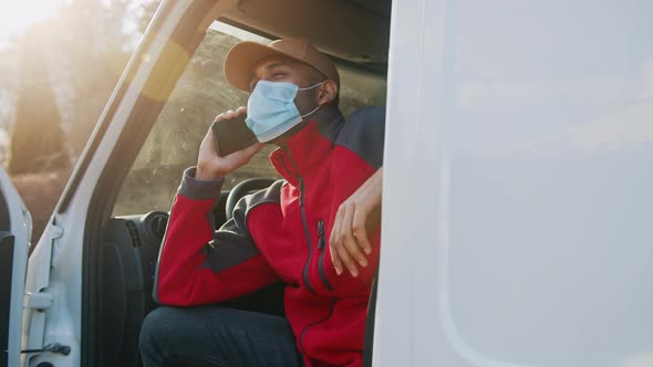Man with Medical Mask Sitting on the Drivers Seat of the Van and Having a Phone Call