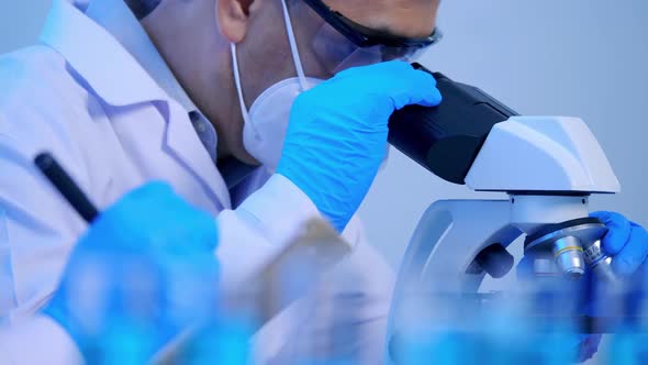 Asian scientist doing some research and looking through a microscope in laboratory.