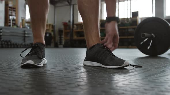 Front view low section of an athletic Caucasian man tying his shoelaces