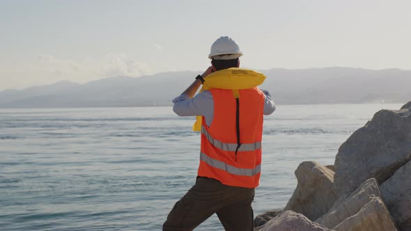 Young Naval Engineer Man Controls the Sea From the Port with Binoculars